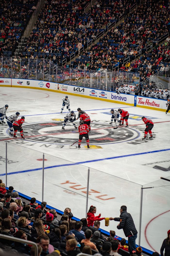 Home Intense hockey face-off amidst cheering crowd in Québec's vibrant stadium, showcasing sports energy.
